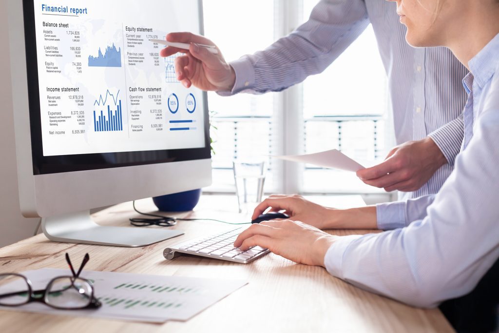 Business men looking at financial reports on a computer